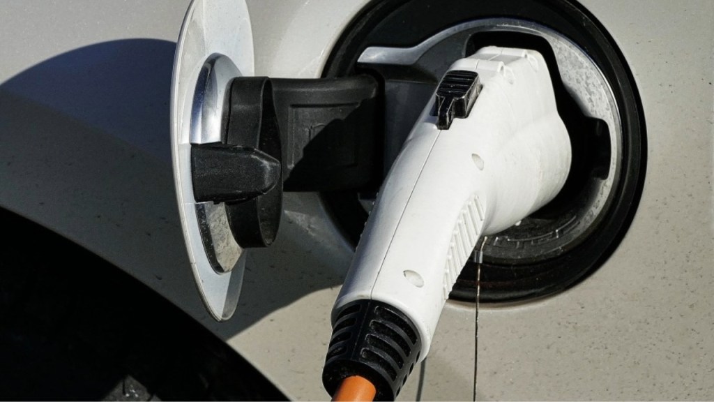 Close-up of an electric vehicle charging connector plugged into a car's charging port.