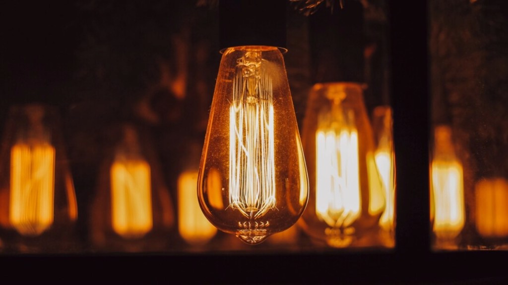 Close-up of a glowing vintage light bulb surrounded by blurred warm-toned lights, creating a cosy atmosphere.