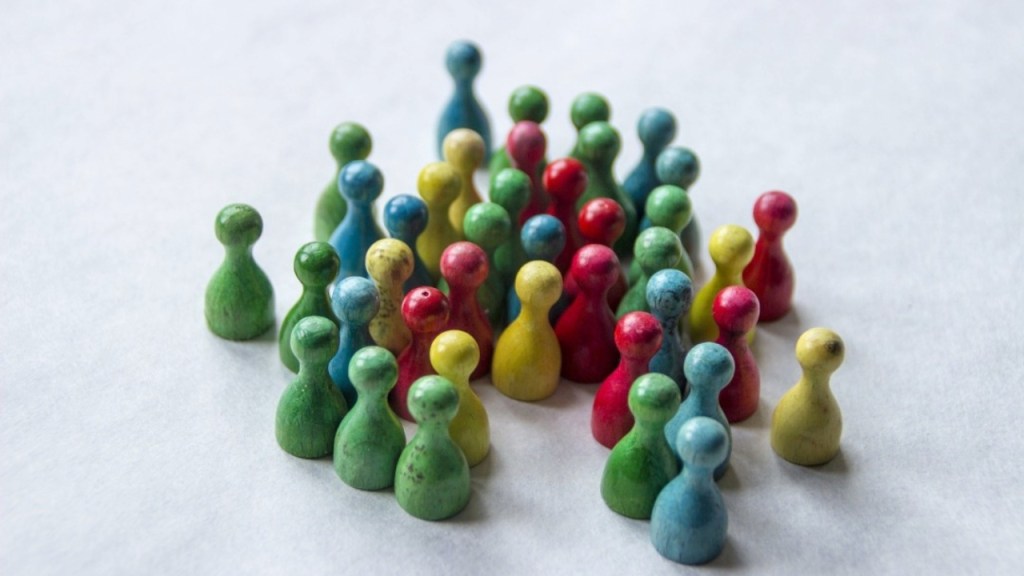 A collection of colourful wooden game pieces, resembling pawns, arranged in a clustered formation on a white background.